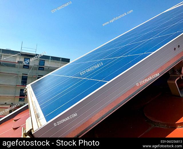house roof with solar panels on top in a newly built area against great blue sky