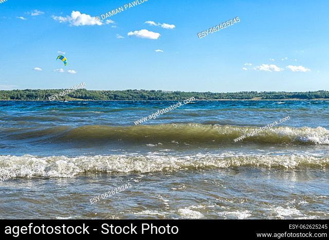 Wavy lake with a lonely kiteboarder flying over the water