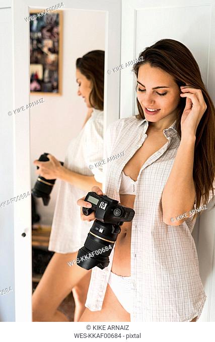 Smiling young woman with camera at home