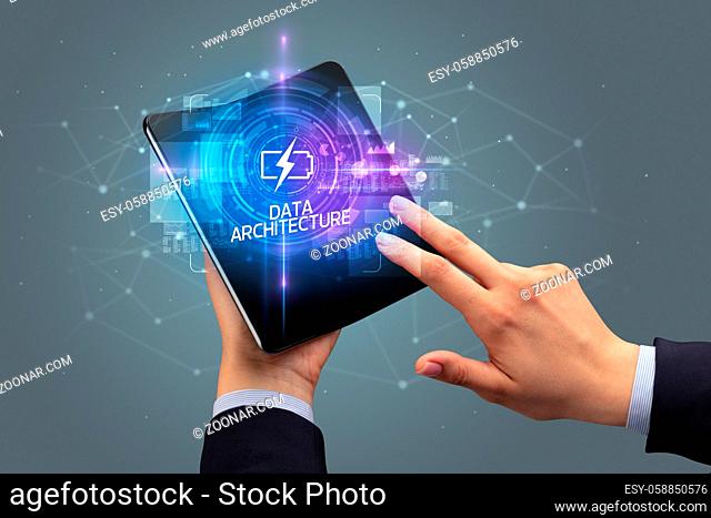 Businessman holding a foldable smartphone with CYBERNETICS inscription, new technology concept DATA ARCHITECTURE