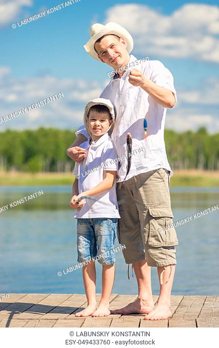 happy fishermen on the pier with a big fish on the hook, fishing on the lake