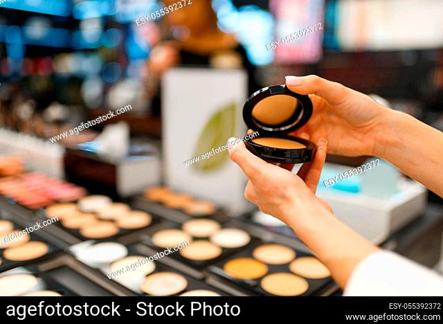 Woman choosing powder in cosmetics store. Buyer at the showcase in luxury beauty shop salon, female customer in fashion market