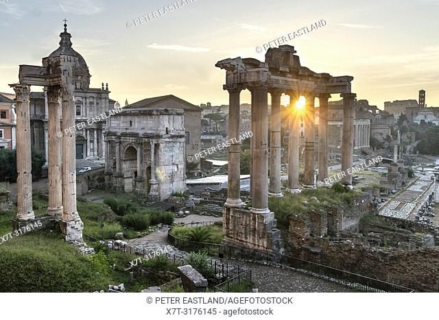 Looking across The Roman Forum at dawn, from the Capitoline Hill, with the temple of saturn in the foreground and the Colosseum in the distance, Rome, Italy