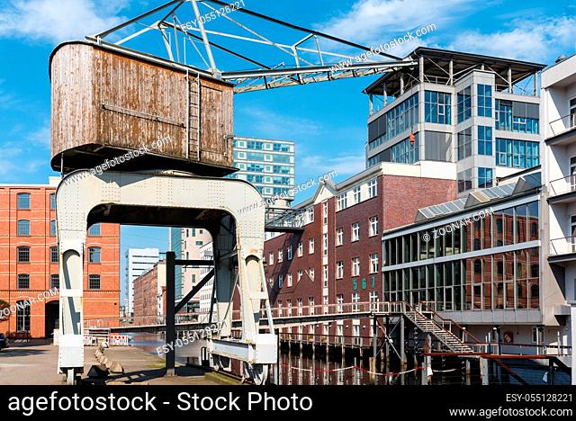 Historical harbour crane in the Harburg inland port. Old converted warehouses and new office buildings in the harbour. The city and the district are part of the...