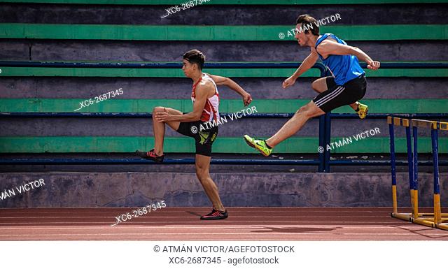 sports boy doing Hurdling on an athletic piste