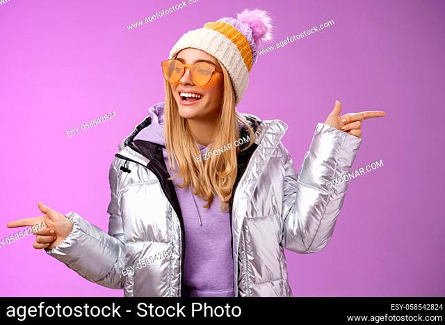 Cool sassy friendly-looking blond girl pointing different sides right left choose which way go look delighted carefree enjoy awesome winter vacation wear...