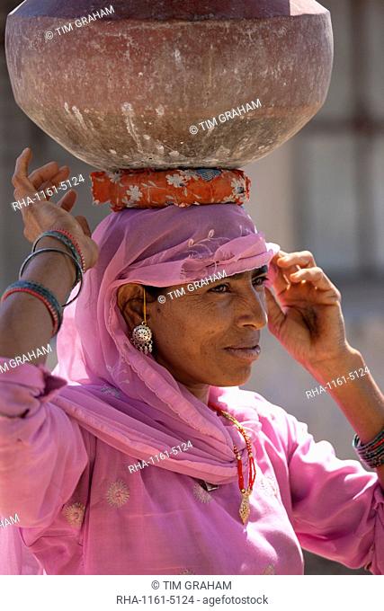 Indian woman in sari fetching water pots from well at Jawali village in Rajasthan, Northern India