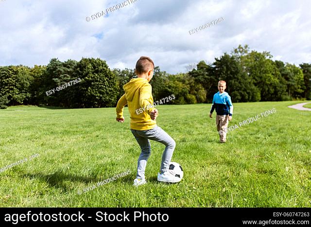 happy little boys with ball playing soccer at park