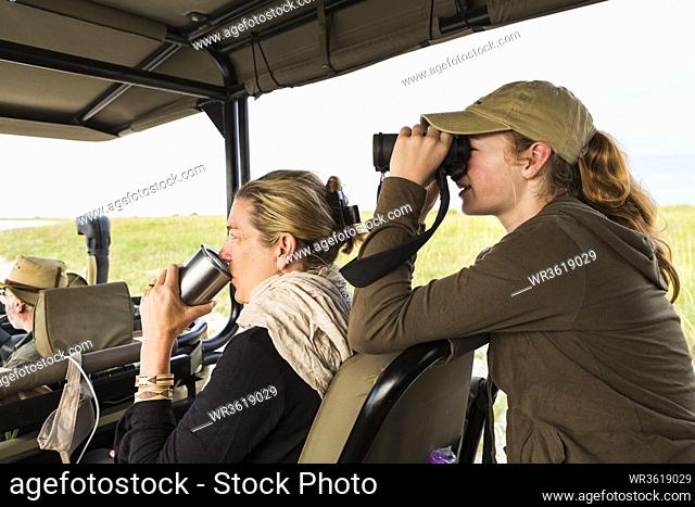 13 year old girl with binoculars on safari vehicle, Botswana