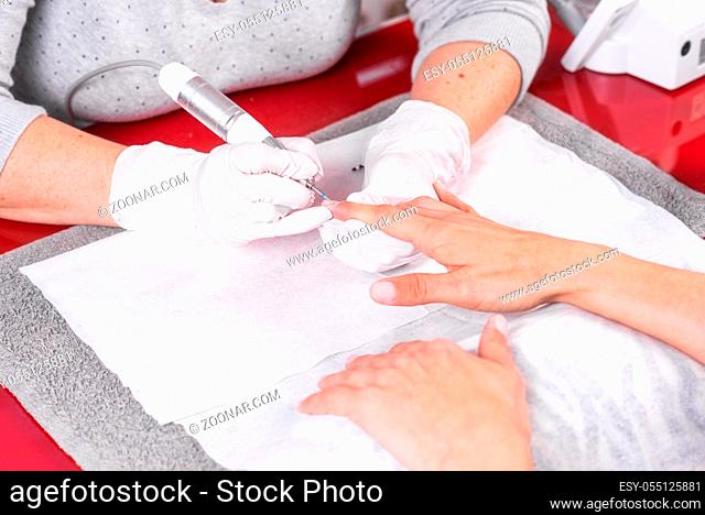 Professional manicure process, cleaning the nails with a manicure milling cutter, at beutician salon