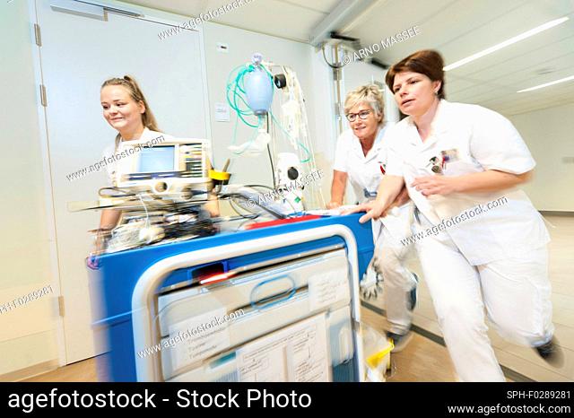 Geriatric hospital ward. Nurses running through the hall of a hospital geriatric ward with a trauma crash cart