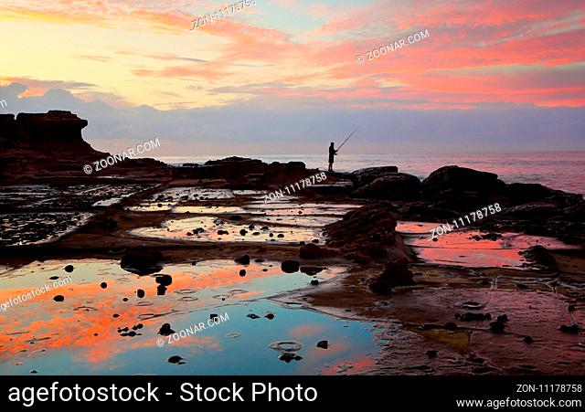 Low tide reflections of sunrise on the rock shelf. Wollongong NSW Australia
