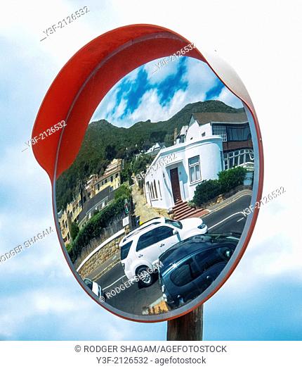 A pole-mounted mirror at an obscured intersection, allows drivers to see “around the corner”