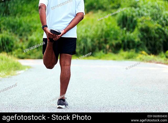 Close up Asian young athlete sport runner black man wear watch lift feet stretching legs and knee before running at the outdoor street health park