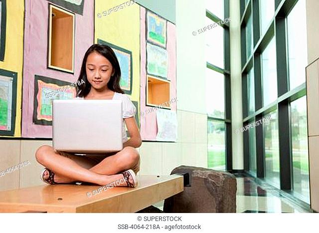 Middle school student using a laptop in a library