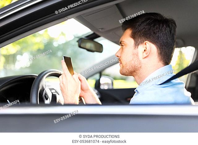 man driving car and using smartphone