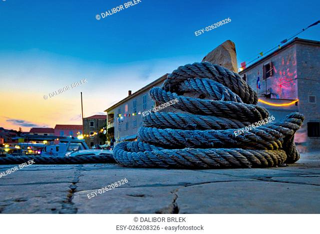 Wound boat rope on mooring bollard evening view, mediterranean village