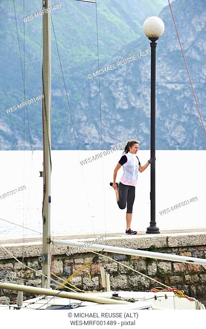 Italy, Trentino, jogger stretching at Lake Garda