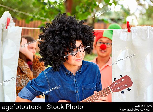 Kind mit Perücke beim Gitarre spielen bei Talentshow Auftritt im Sommercamp