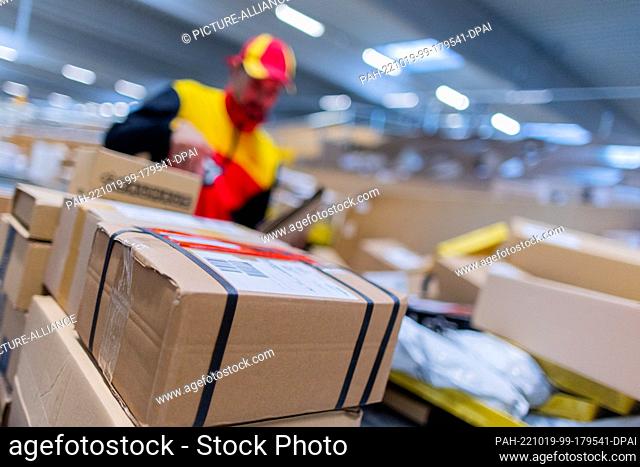 19 October 2022, North Rhine-Westphalia, Cologne: A parcel delivery driver sorts and puts parcels into a delivery vehicle at a Deutsche Post DHL delivery base