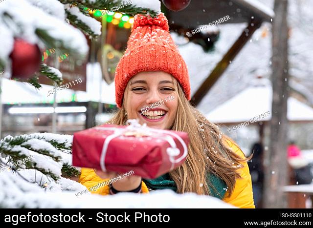 Smiling young woman holding Christmas present outdoors