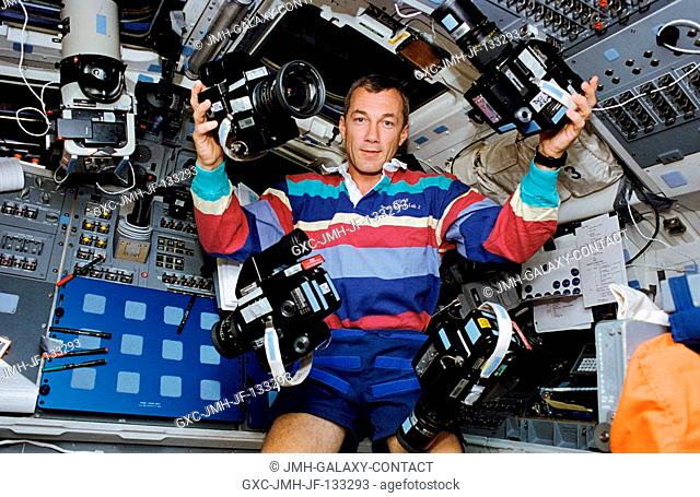 Astronaut Terrence W. Wilcutt, pilot, takes advantage of the weightless environment of space to juggle five cameras onboard the Space Shuttle Endeavour's flight...
