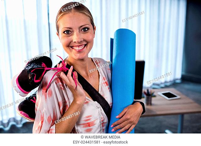 Casual businesswoman with yoga mat and sports shoes