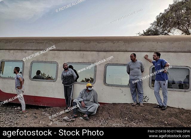 18 April 2021, Egypt, Sandahur: People inspect the damaged wagons of a passenger train that derailed at the village of Sandahur near Banha in Qalyubia...