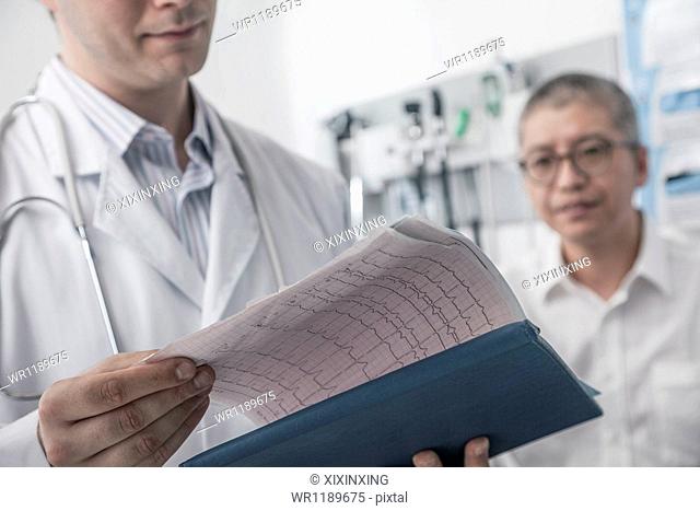 Doctor checking medical chart with patient in the background