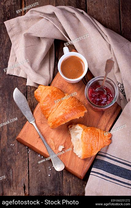 Croissant with jam and coffee on a wooden background. Top view