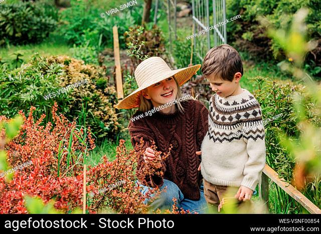 Smiling mother showing flower to son in garden