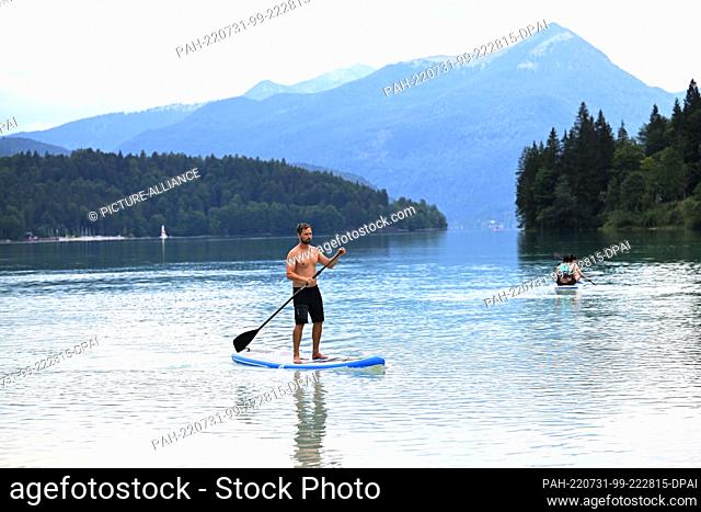 31 July 2022, Bavaria, Niedernach: Stand-up paddler Moritz Müller rides his board in Lake Walchen. Photo: Felix Hörhager/dpa