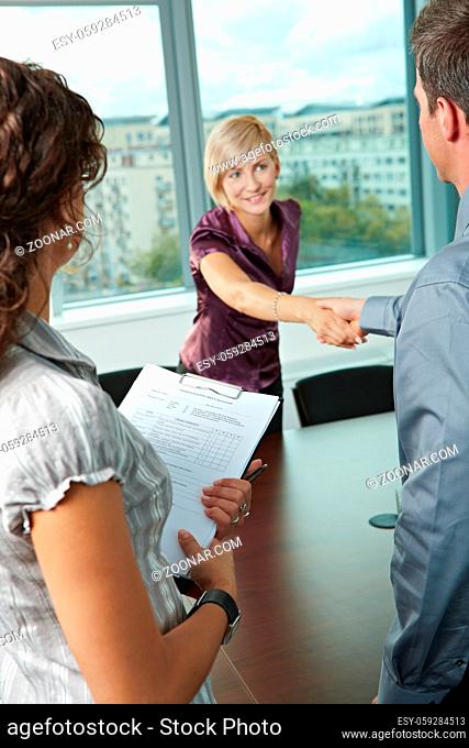 Successful job interview - happy employee shaking hands, smiling. Focus places on questionnarie in front, reults are excellent