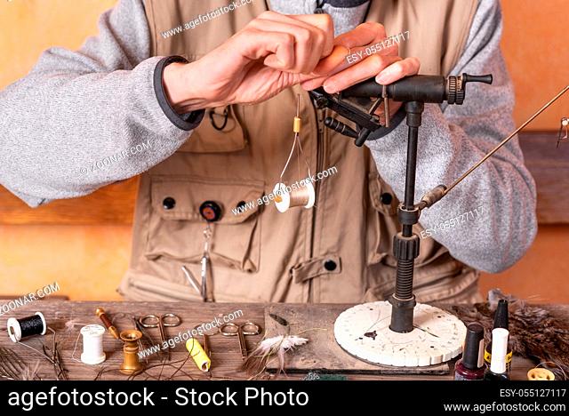 Man making trout flies. Fly tying equipment and material for fly fishing preparation