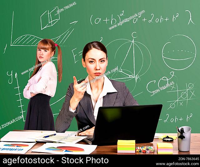 Teacher sitting at the desk and young pupil white on blackboard at classroom