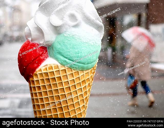 31 March 2022, Lower Saxony, Aurich: A display in the shape of an oversized ice cream cone stands downtown as snow falls