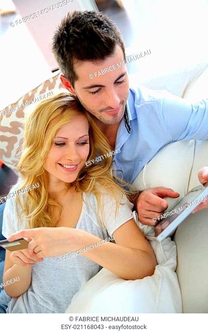 Cheerful young couple doing online shopping with tablet