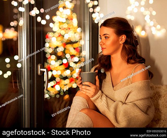 woman with cup of coffee at window on christmas