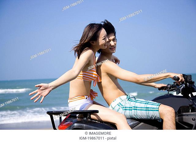 Young couple sitting on the motorcycle and smiling happily