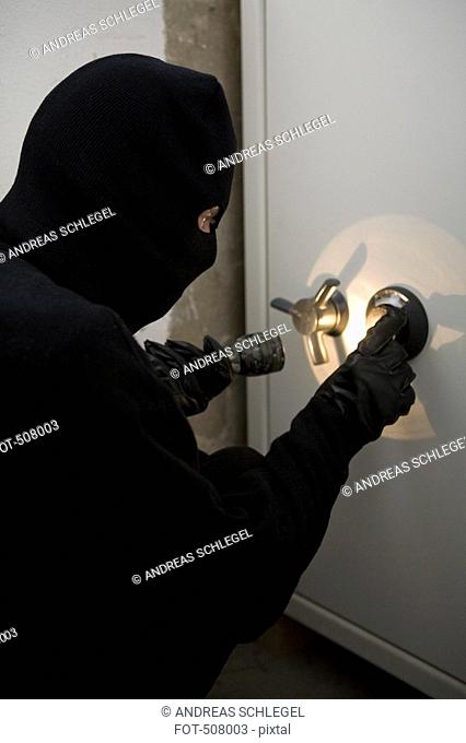 A thief unlocking a combination safe