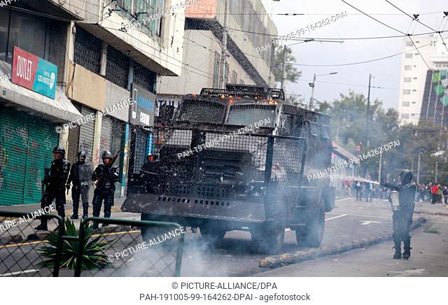 04 October 2019, Ecuador, Quito: An armoured vehicle belonging to the security forces burns during riots as part of a protest against fuel price increases