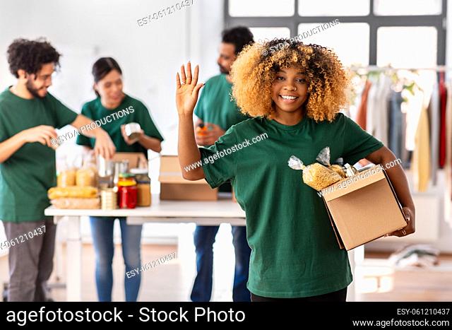 female volunteer with food in box waving hand