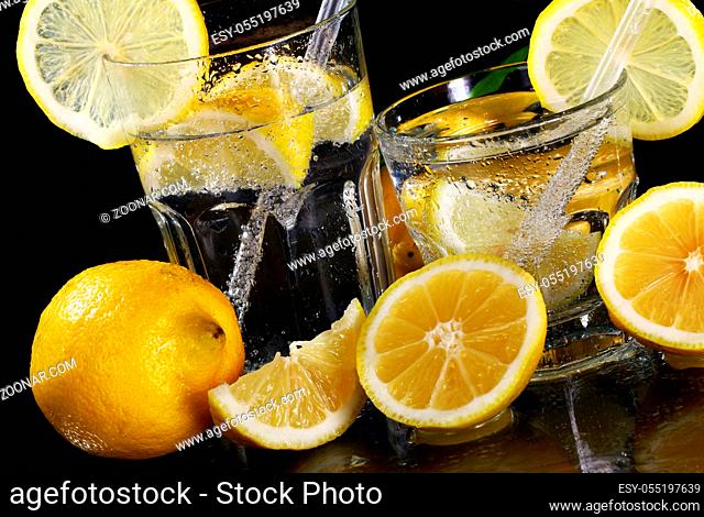 Cocktail with fresh wet lemons on black background