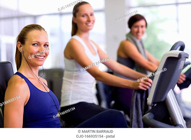 Portrait of smiling woman on exercise bike in gymnasium