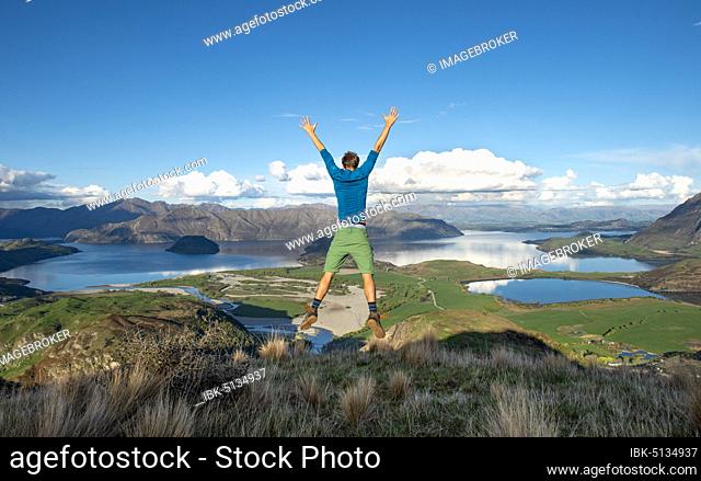 Hiker jumps in the air, view of Wanaka Lake and mountains, Rocky Peak, Glendhu Bay, Otago, South Island, New Zealand, Oceania