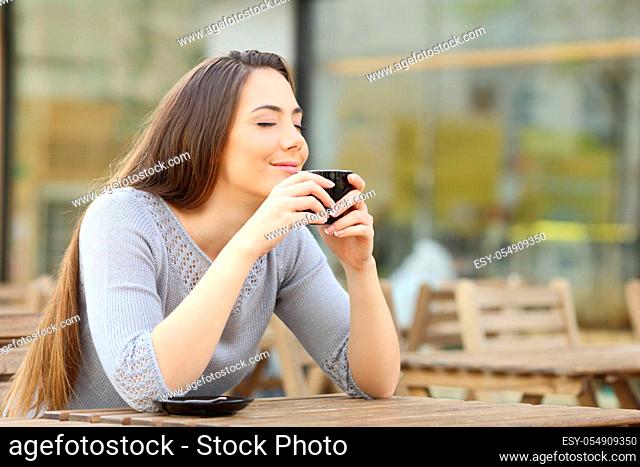 Satisfied woman smelling her cup of coffee on a restaurant terrace