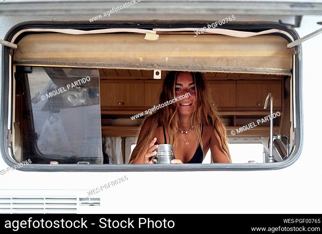 Woman looking through window of camping van