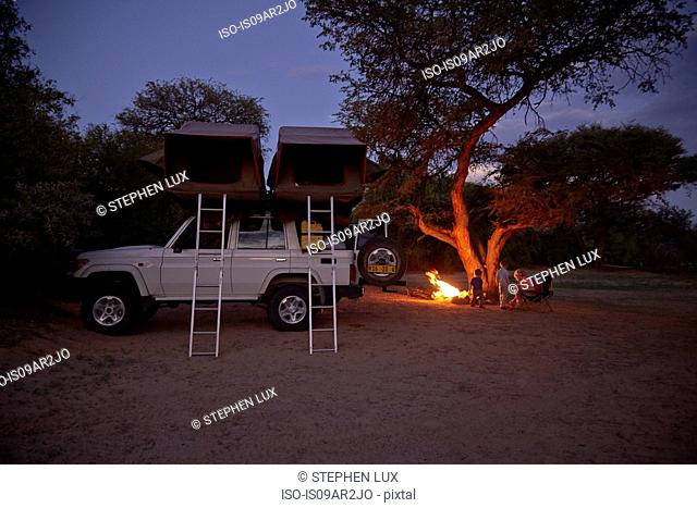 Off road vehicle parked, family sitting around campfire, Purros, Kaokoland, Namibia