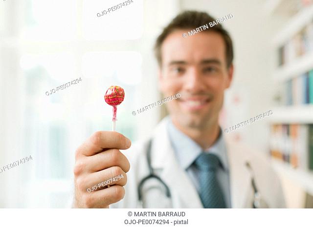 Doctor holding out lollipop in doctor’s office