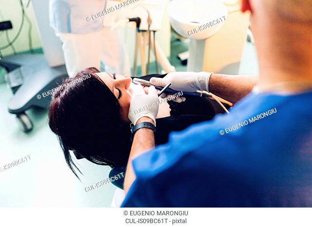 Dentist carrying out dental procedure on female patient